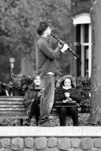 Young male playing clarinet on the street in Delft