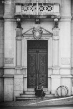 Female sitting on steps of of large stately door, Lisbon