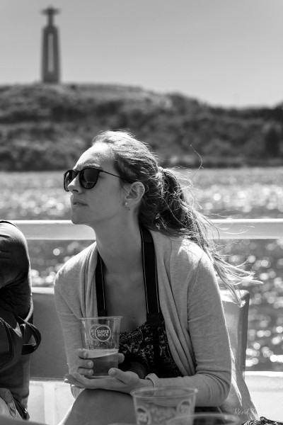 Young female with beer on a boat to Belem, Lisbon, resembling Natalie Portman