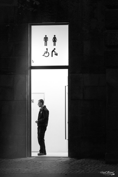 Male standing in front of the public toilets at night, Prague