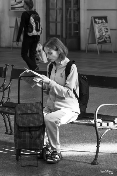 Nerdy girl reading at Prague station
