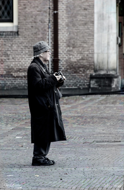Old male tourist with camera on Binnenhof, The Hague